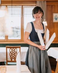 Mitarbeiterin in traditioneller Tracht beim Eindecken im Restaurant des Hotel Adler.
