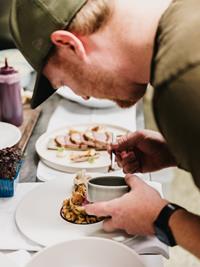 Junger Koch bei der kreativen Zubereitung eines Gourmettellers in der Hotel Adler Küche.