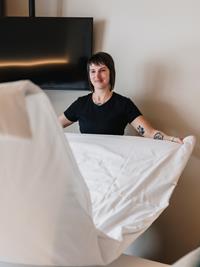 Mitarbeiterin beim Bettenmachen im Hotelzimmer.