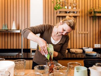 Mit Motivation neu durchstarten im Hotel Adler Mitarbeiterin füllt mit Sorgfalt Trockenfrüchte in Gläser im Frühstücksbereich des Hotels.