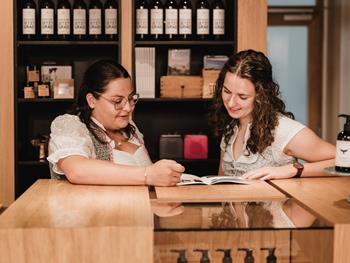 Zwei Mitarbeiterinnen im Gespräch an der Rezeption im Hotel Adler, umgeben von regionalen Produkten.