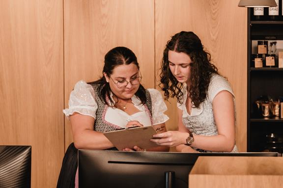 Einarbeitung mit Herz und Kompetenz Zwei Mitarbeiterinnen an der Rezeption des Hotel Adler.