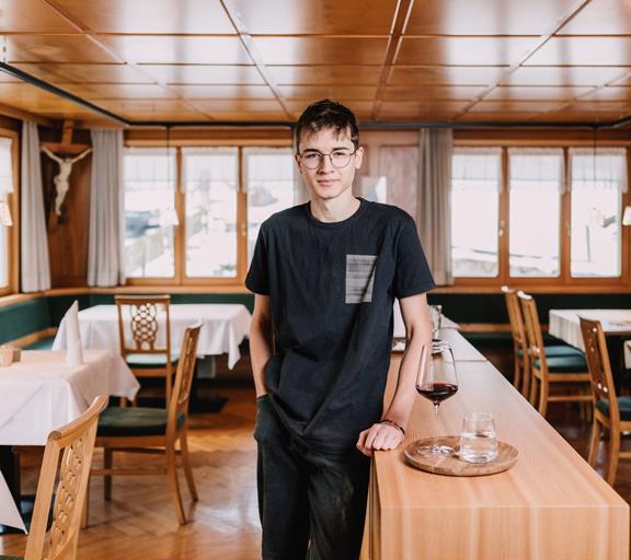Dein Einstieg in den Tourismus Auszubildender im Service mit Stolz im Gastraum des Hotel Adler.