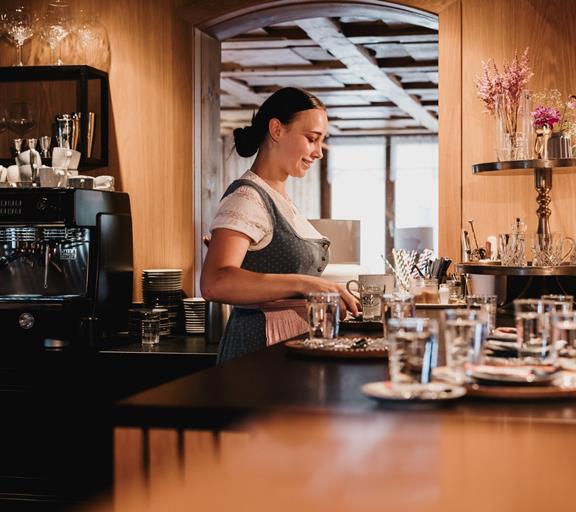 Hier findest du garantiert die richtige Stelle Junge Mitarbeiterin bereitet an der Hotelbar Kaffee vor.