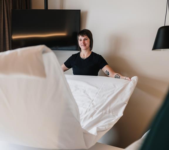 Mitarbeiterin beim Bettenmachen im Hotelzimmer.